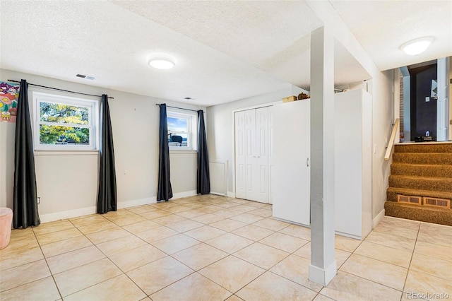 unfurnished room featuring a textured ceiling, light tile patterned flooring, and plenty of natural light