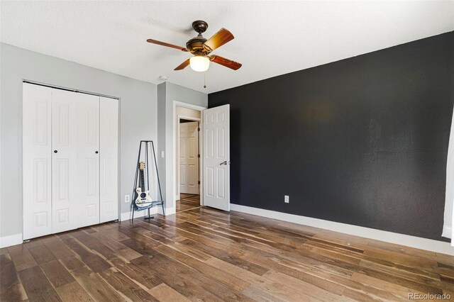 unfurnished bedroom featuring dark wood-type flooring, ceiling fan, and a closet