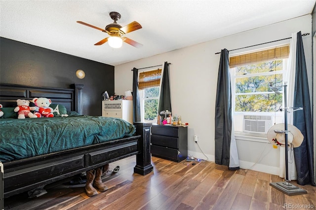 bedroom featuring cooling unit, hardwood / wood-style flooring, and ceiling fan