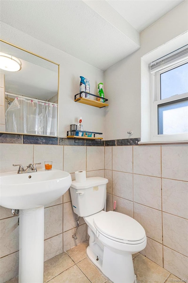 bathroom with tile walls, tile patterned floors, toilet, and sink