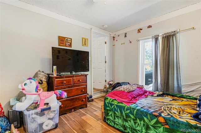 bedroom featuring a textured ceiling and light hardwood / wood-style flooring