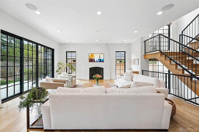 living area featuring a fireplace, light wood-style floors, recessed lighting, and stairs