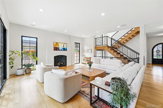 living area featuring light wood finished floors, stairway, recessed lighting, a fireplace, and baseboards