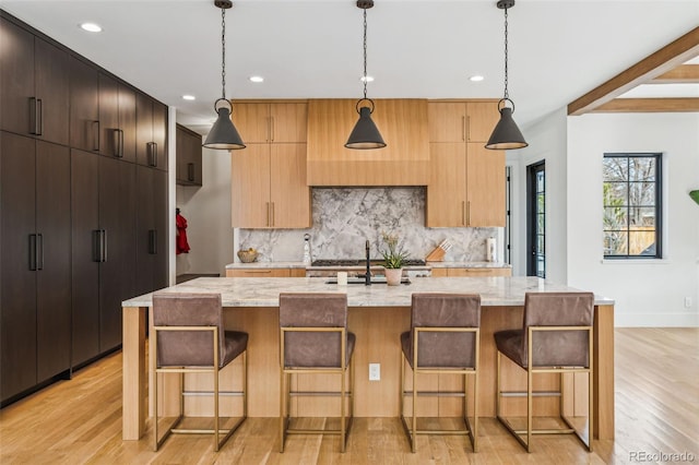 kitchen with tasteful backsplash, light wood-style floors, recessed lighting, modern cabinets, and an island with sink