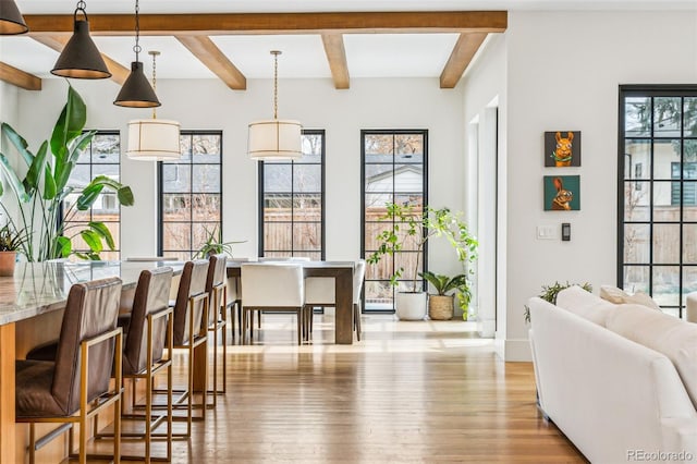 dining space with wood finished floors, beam ceiling, and baseboards