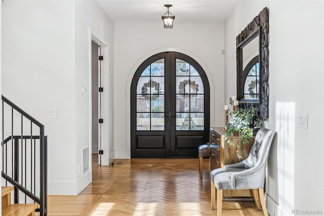 foyer entrance featuring arched walkways, french doors, stairs, and baseboards