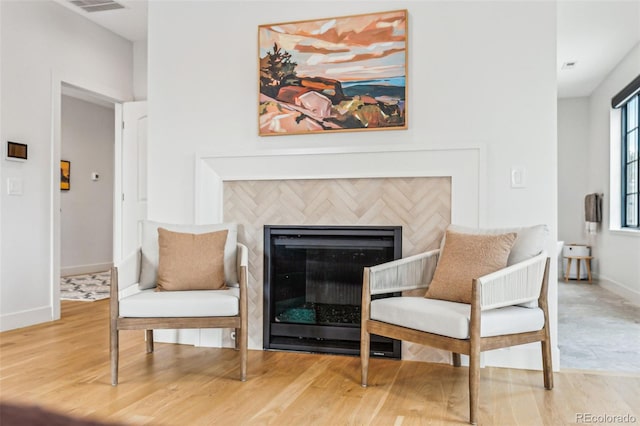 living area featuring wood finished floors, baseboards, and a tile fireplace