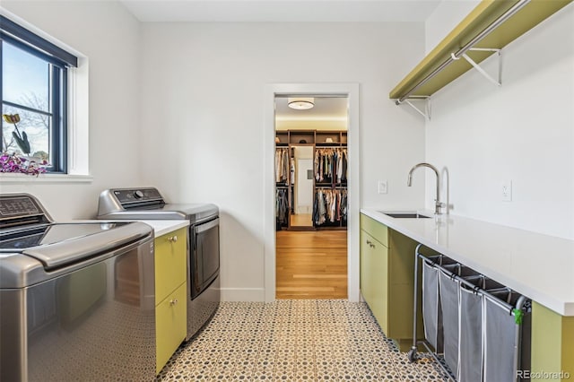 laundry area featuring washer and clothes dryer, cabinet space, light floors, and baseboards