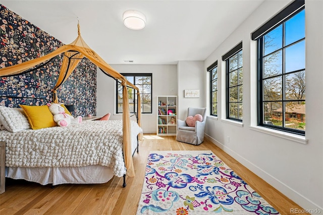 bedroom featuring multiple windows, wood finished floors, and baseboards