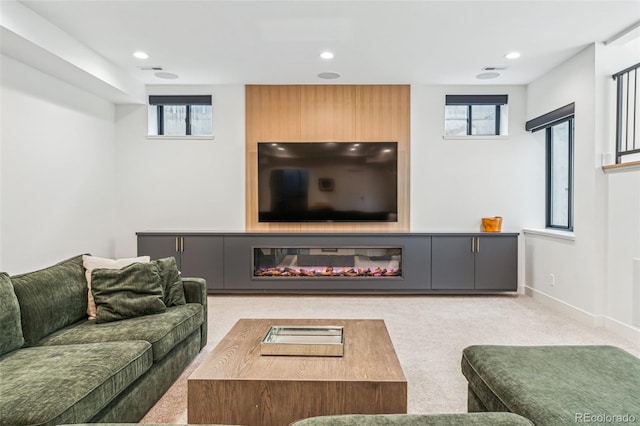 carpeted living room featuring recessed lighting, a glass covered fireplace, and baseboards