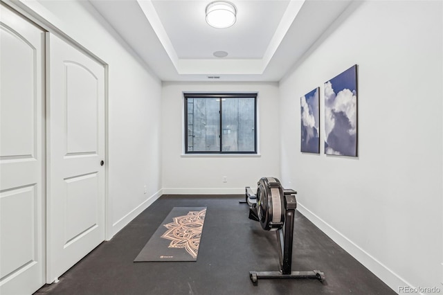 workout area featuring baseboards and a raised ceiling