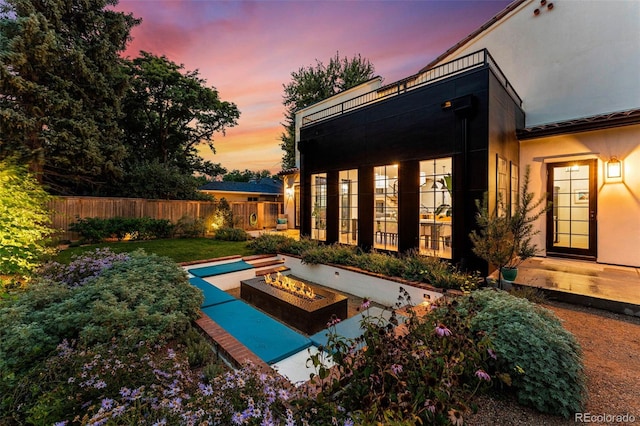 back of property at dusk with a fire pit and stucco siding