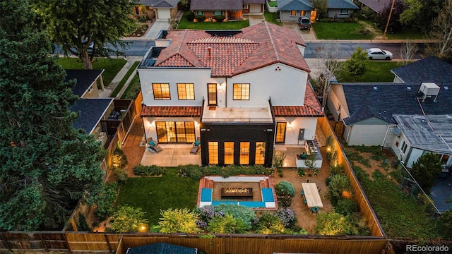 rear view of house with stucco siding, a tile roof, a fenced backyard, and a patio area
