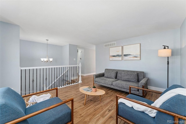 living area featuring a chandelier, baseboards, visible vents, and wood finished floors