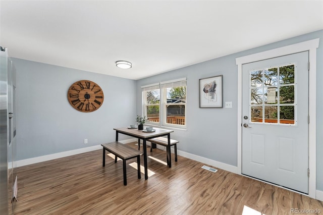 dining room with light wood finished floors, visible vents, and baseboards