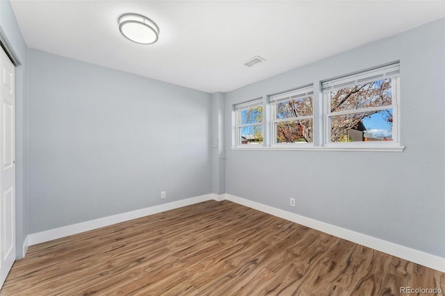 unfurnished bedroom featuring baseboards, a closet, visible vents, and wood finished floors