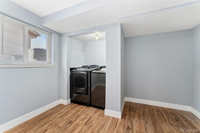 clothes washing area with washing machine and clothes dryer, laundry area, baseboards, and light wood-style floors