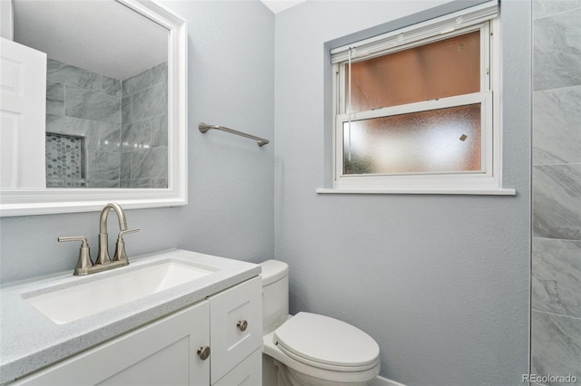 full bath featuring vanity, toilet, and a tile shower