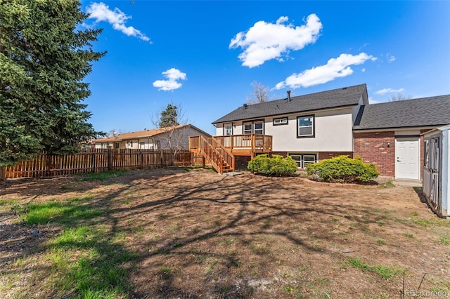 rear view of house with fence, brick siding, stucco siding, stairway, and a wooden deck