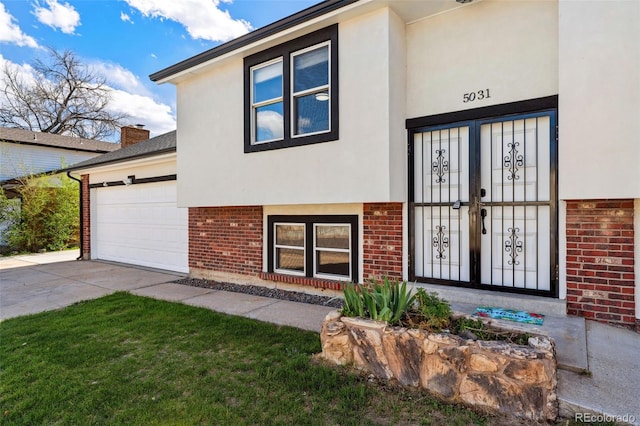 property entrance featuring concrete driveway, an attached garage, stucco siding, and brick siding
