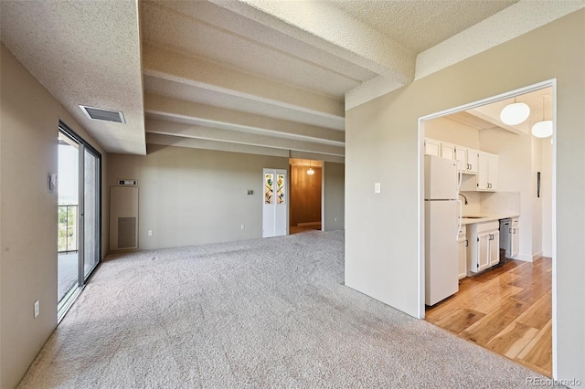 7865 E Mississippi Ave Unit 1504, Denver, CO 80247 - unfurnished living room with light colored carpet, a textured ceiling, and beam ceiling