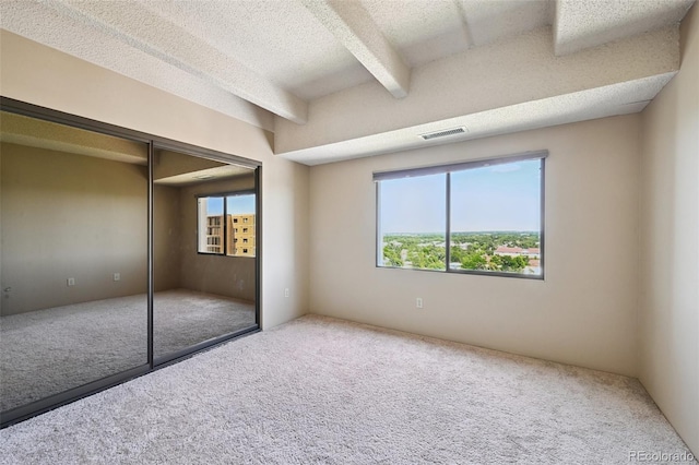 7865 E Mississippi Ave Unit 1504, Denver, CO 80247 - unfurnished bedroom with carpet floors, a closet, beamed ceiling, and a textured ceiling