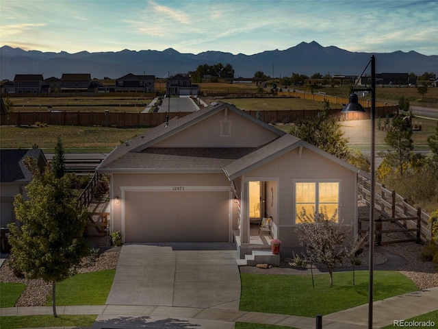 view of front of house featuring a mountain view, a front yard, and a garage