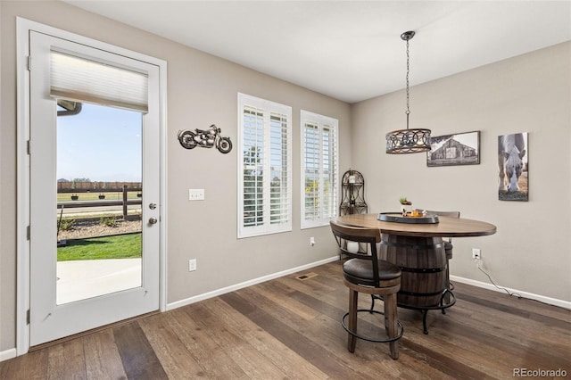 dining area featuring an inviting chandelier, a healthy amount of sunlight, and dark hardwood / wood-style flooring