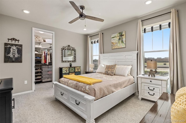 carpeted bedroom with a spacious closet, ceiling fan, and a closet