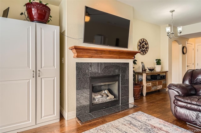 living area with arched walkways, a fireplace, and wood finished floors