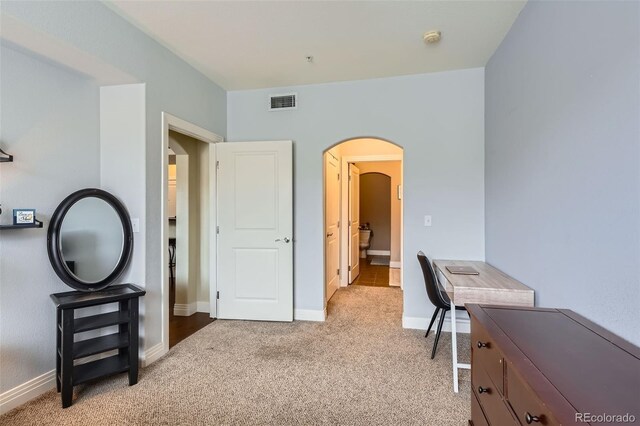 office space featuring arched walkways, light colored carpet, and baseboards