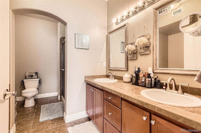 full bathroom featuring toilet, tile patterned flooring, double vanity, and a stall shower