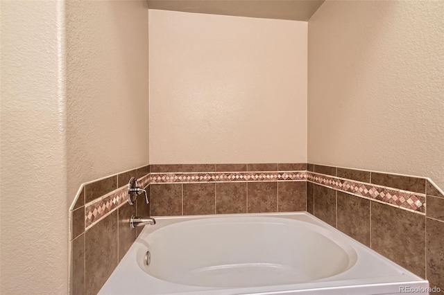 bathroom with a textured wall and a bath