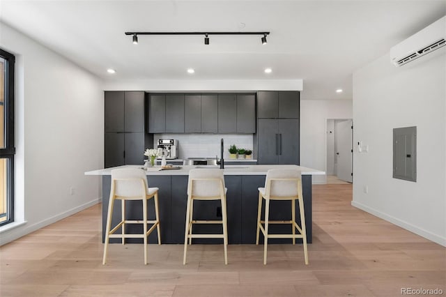 1601 Park Ave Unit 307, Denver, CO 80218 - kitchen featuring electric panel, an AC wall unit, recessed lighting, a sink, and a kitchen bar