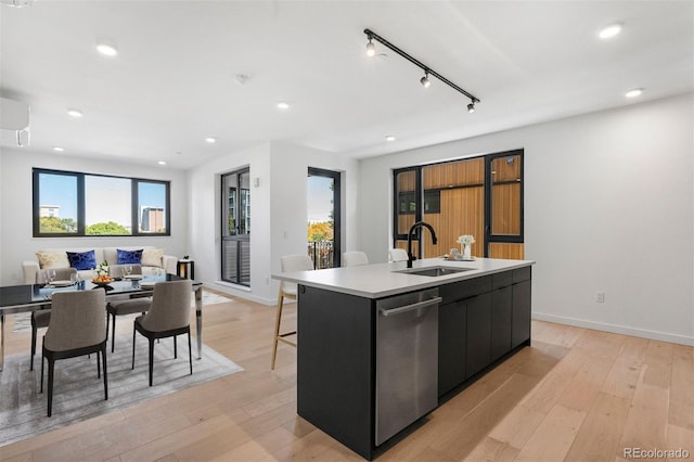 1601 Park Ave Unit 307, Denver, CO 80218 - kitchen featuring a sink, dark cabinets, a kitchen island with sink, stainless steel dishwasher, and light wood-type flooring
