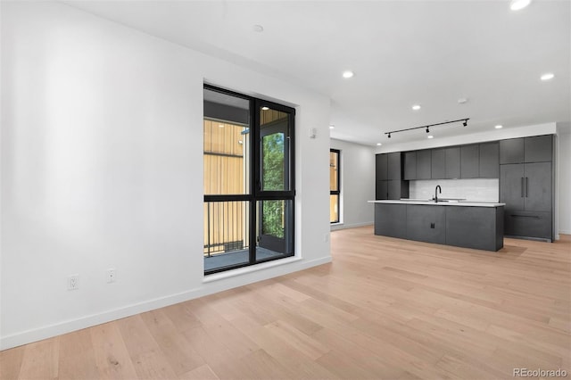1601 Park Ave Unit 307, Denver, CO 80218 - unfurnished living room featuring light wood-type flooring, baseboards, a sink, track lighting, and recessed lighting
