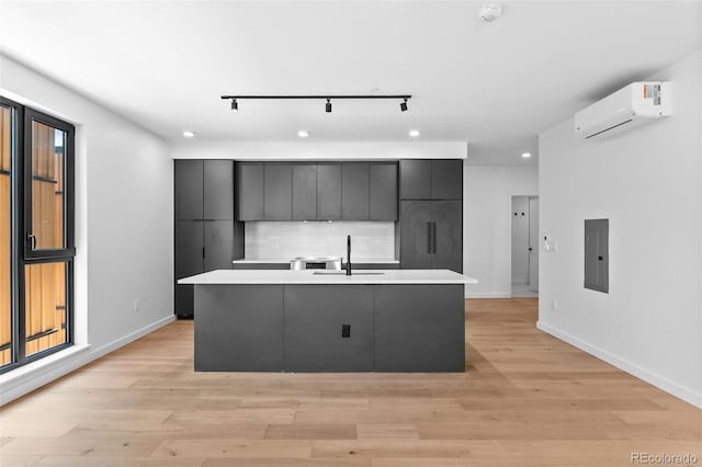 1601 Park Ave Unit 307, Denver, CO 80218 - kitchen with an AC wall unit, electric panel, a sink, light countertops, and a kitchen island with sink
