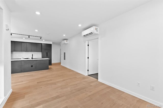 1601 Park Ave Unit 307, Denver, CO 80218 - unfurnished living room with a wall mounted AC, light wood-style flooring, baseboards, track lighting, and recessed lighting