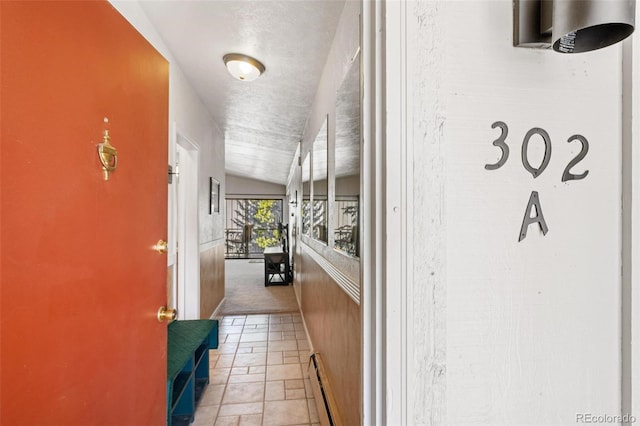 corridor with lofted ceiling and a baseboard heating unit