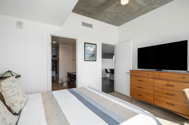carpeted bedroom with ensuite bath and a ceiling fan