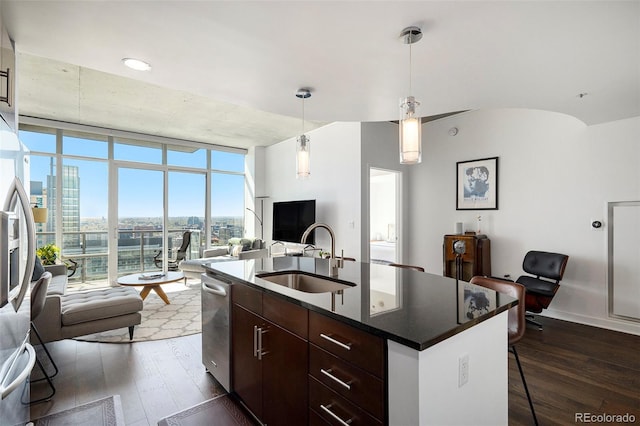kitchen with open floor plan, a sink, dark wood-style floors, dark countertops, and a breakfast bar area