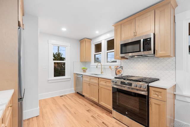 kitchen featuring a sink, stainless steel appliances, light brown cabinets, and light countertops