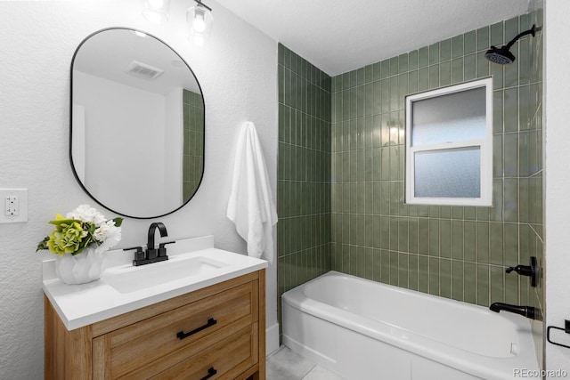 full bath featuring visible vents, bathtub / shower combination, vanity, and a textured wall