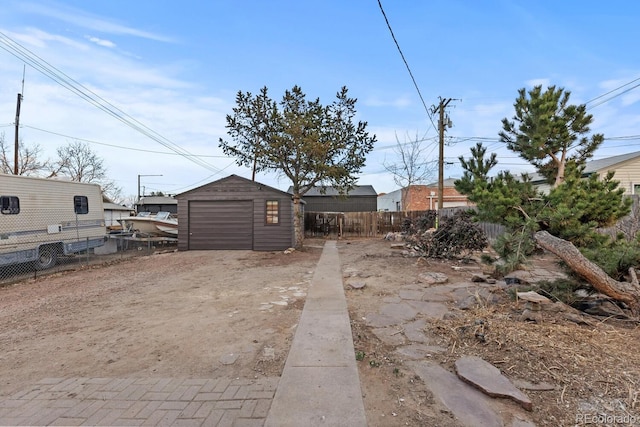 view of yard featuring a garage, an outdoor structure, driveway, and fence