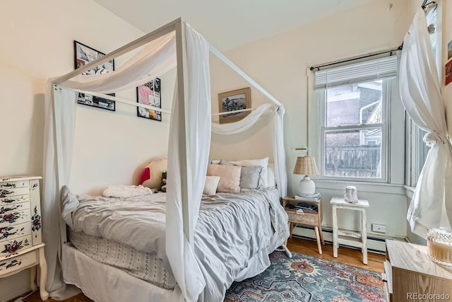 bedroom featuring wood-type flooring and a baseboard heating unit