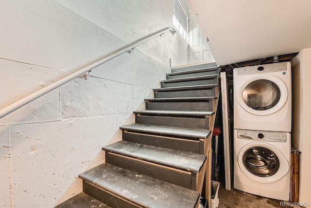 stairs featuring stacked washer / drying machine