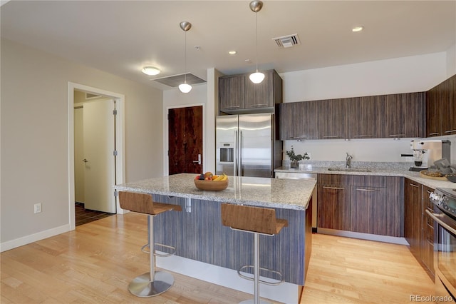 kitchen featuring visible vents, electric range, light wood-style floors, high quality fridge, and a sink