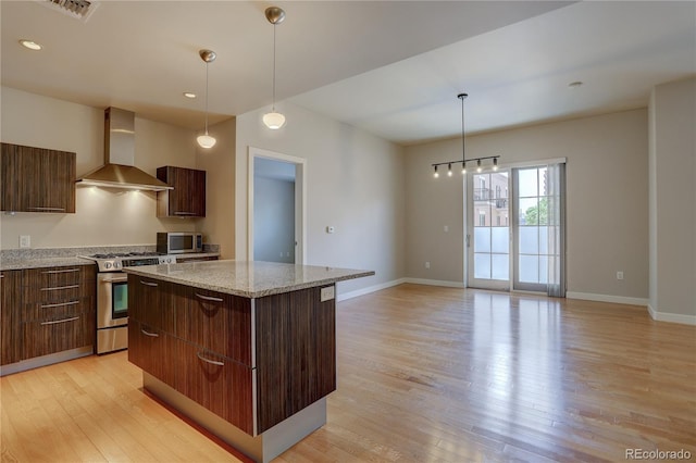 kitchen featuring light wood-style floors, wall chimney exhaust hood, modern cabinets, and stainless steel appliances