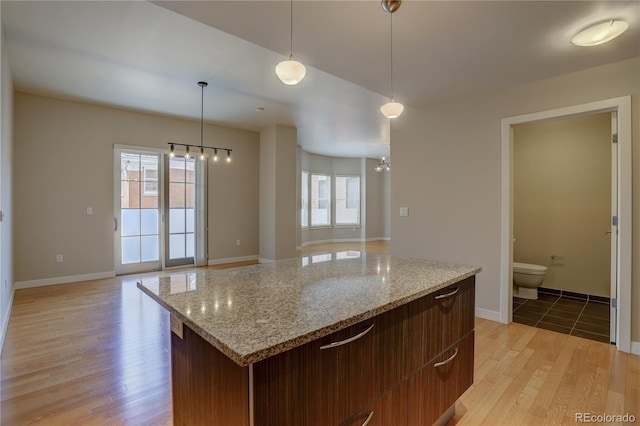 kitchen featuring open floor plan, hanging light fixtures, light wood-type flooring, and a notable chandelier