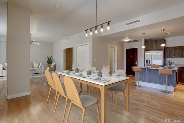 dining room with light wood-style floors, rail lighting, visible vents, and baseboards